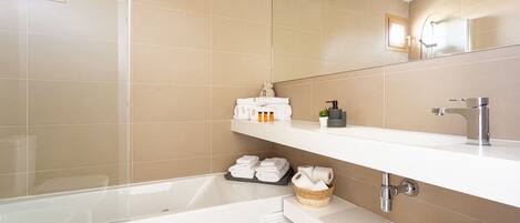 A modern bathroom with a bathtub, a vanity with a mirror, and shelves with toiletries.