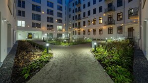 Ein Innenhof eines Mehrstöckigen Hotels mit einem zentralen Weg, umgeben von Grünpflanzen und beleuchtet durch Lichterketten.
