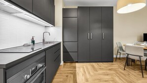 Eine moderne Küche mit dunklen Schränken, einer Edelstahlspüle und einem Essbereich mit Tisch und Stühlen.