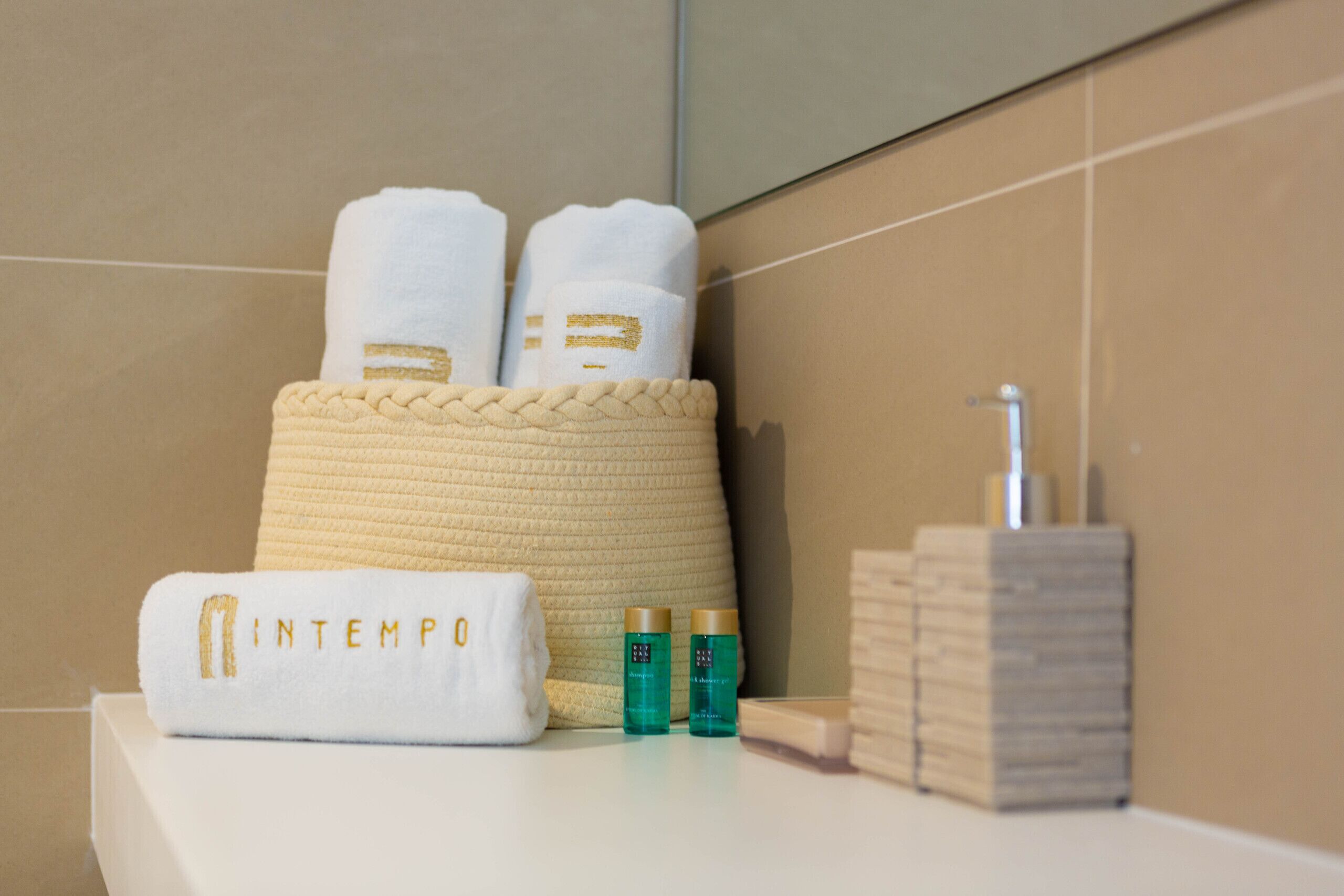 Un baño con una toalla blanca, dos botellas de artículos de tocador y una pila de toallas dobladas.