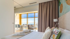 Ein Hotelzimmer mit einem großen Bett, Blick auf die Stadt und einem Balkon mit Stühlen und einem Tisch.