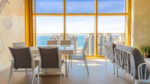 Ein moderner Essbereich mit großem Fenster und Blick auf eine Stadtlandschaft und das Meer.