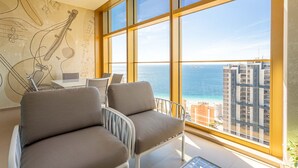 Ein modernes Wohnzimmer mit einem großen Fenster mit Blick auf eine Stadtlandschaft und das Meer.