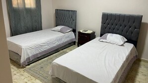 Two single beds with grey headboards, a small bedside table, and a patterned rug. - Timo Pyramids View : Deluxe Twin Room (Giza Governorate)