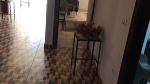 A hallway with a checkered floor pattern leading to a dining area with a table and chairs. - Timo Pyramids View : Deluxe Twin Room (Giza Governorate)