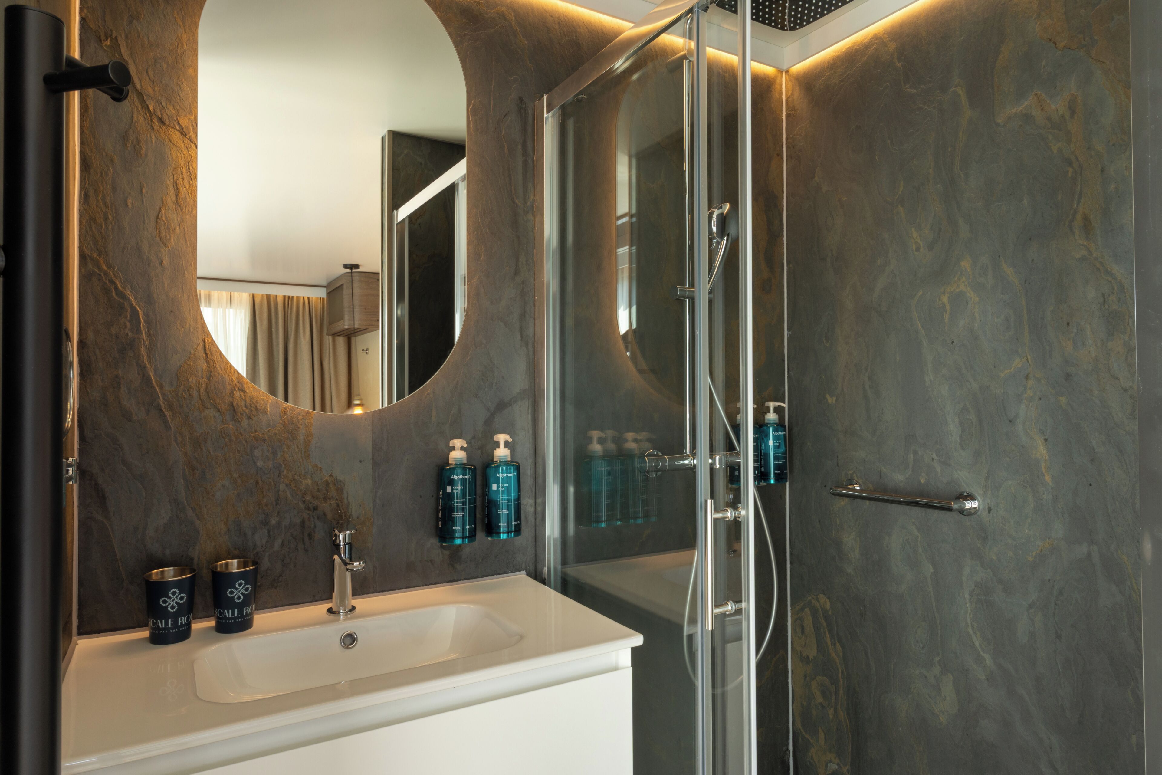 A bathroom with a large mirror, a sink, and a shower area.