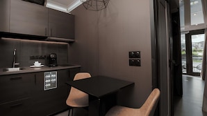 Una cucina moderna con zona pranzo, caratterizzata da un tavolo e sedie neri, una macchina da caff è e un forno a incasso.