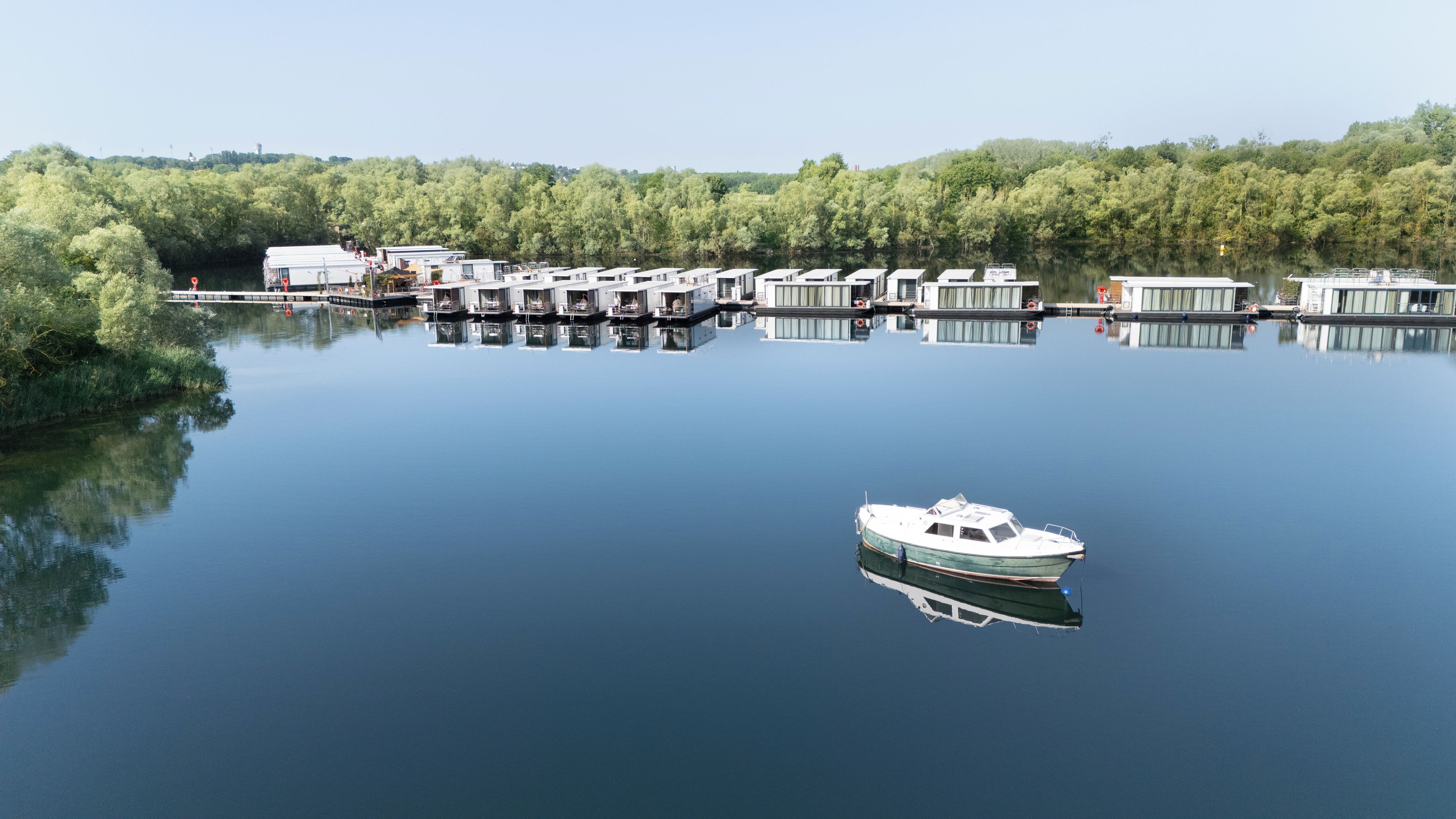 A calm lake with floating homes and a small boat.