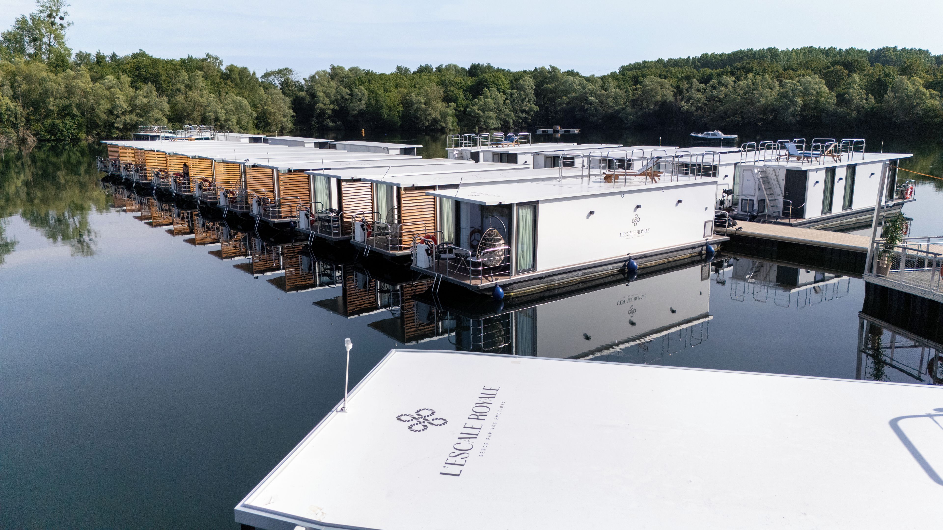 Ein schwimmendes Hotel mit mehreren Ebenen, Außenbereichen zum Sitzen und einem Anlegesteg.