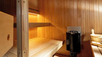Un sauna con paredes y bancos de madera, un calentador Harvia y un banco con respaldo curvo.