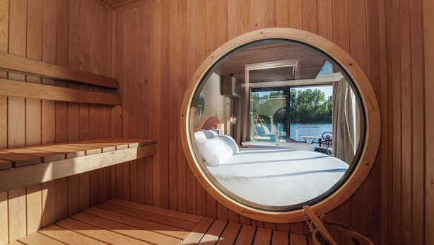 Letto a finestra circolare con vista su una terrazza e sull'acqua.