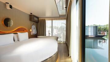 A modern hotel room with a large bed, a bathroom with a bathtub, and a view of a body of water.