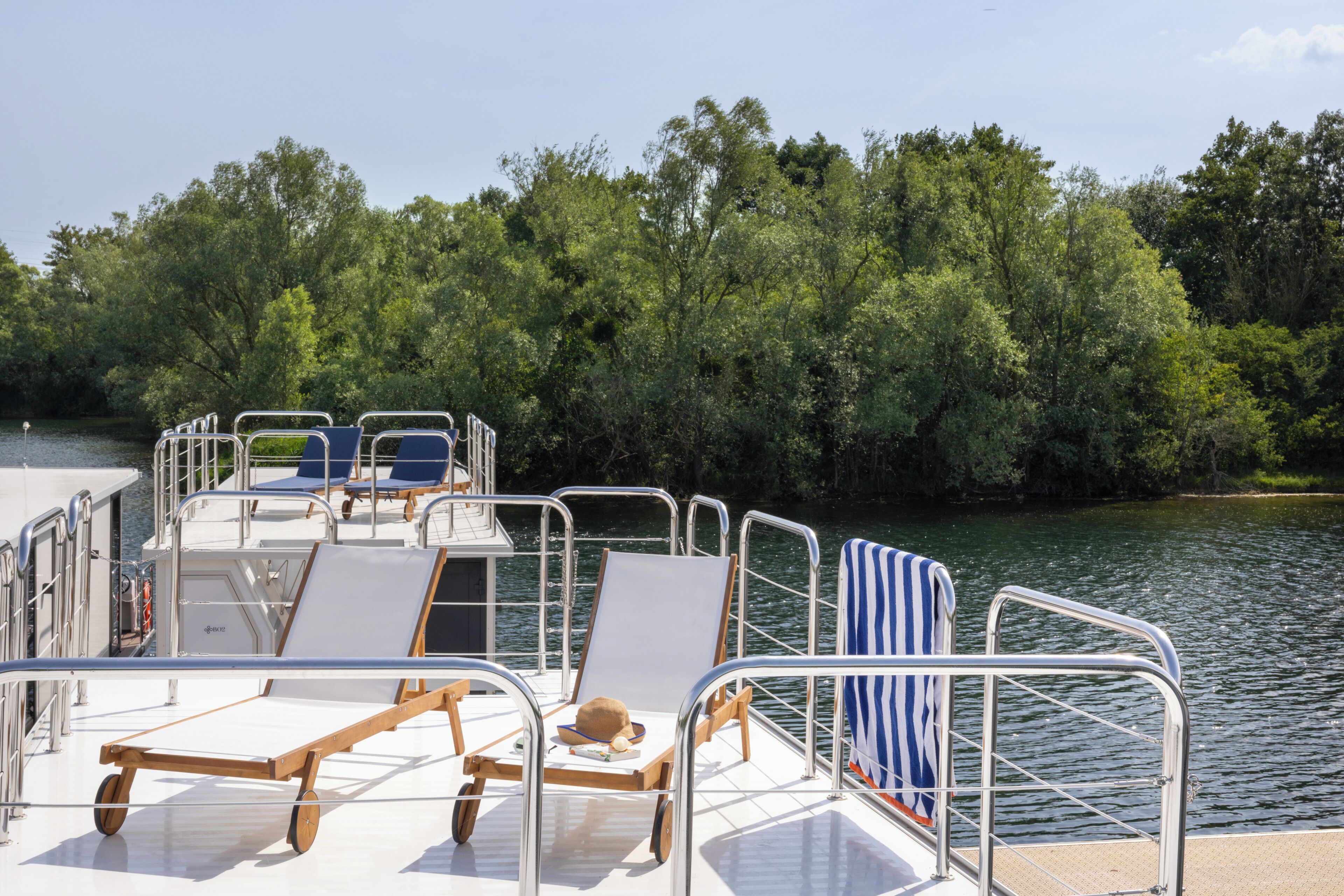 Ein Bootsdeck mit Liegestühlen, einem kleinen Tisch und einem Hut.
