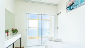 A hotel room with a bed, a white desk, a large window with a view of the sea, and a painting on the wall. - Intempo by Holuxe - 272 - 27th floor (Benidorm)