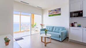 A modern living room with a blue sofa, a small round table, and a view of the ocean through large windows. - Intempo by Holuxe - 272 - 27th floor (Benidorm)