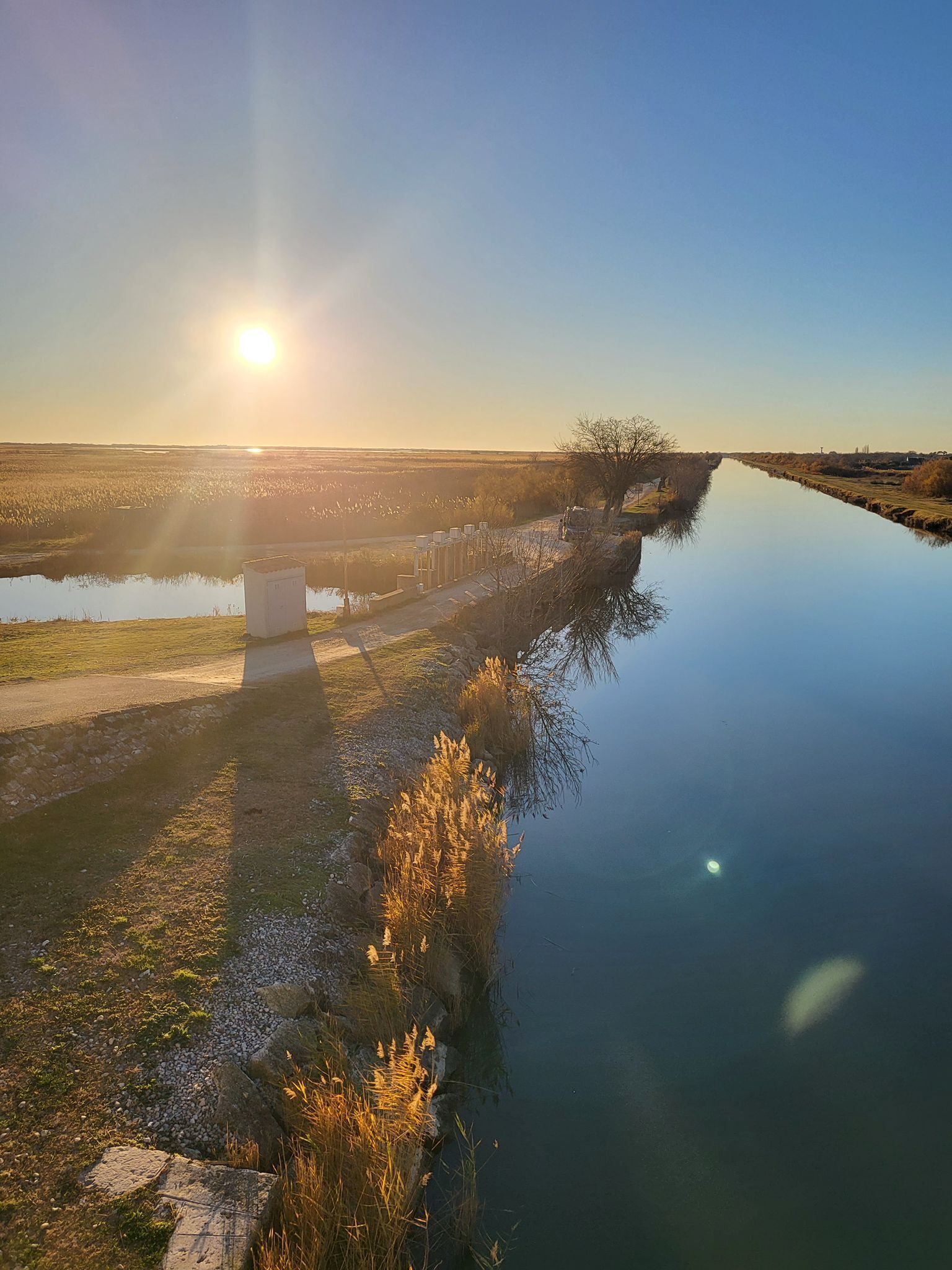 A calm river with a bridge and a clear sky.