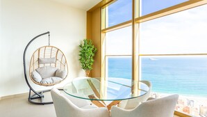 Een moderne kamer met een glazen tafel, een rieten stoel en uitzicht op de oceaan.