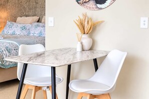 Une pièce comprenant un lit, une table à manger avec des chaises et un interrupteur fixé au mur.
