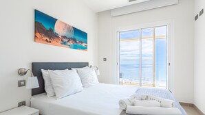 Une chambre d’hôtel moderne avec un grand lit, une table de chevet, une lampe et un tableau représentant un paysage de montagne.
