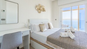 Habitación de hotel con cama, escritorio, silla, ventana grande con vistas y un adorno decorativo en la pared.