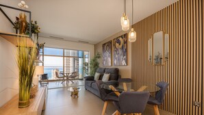 Un salon moderne comprenant un canapé, une table à manger, des chaises et une grande fenêtre donnant sur la ville.