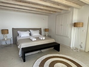 A bedroom with a bed, bedside lamps, a bench, and a rug. - Topos exclusive Mykonos-villa Alisahnea (Mykonos)