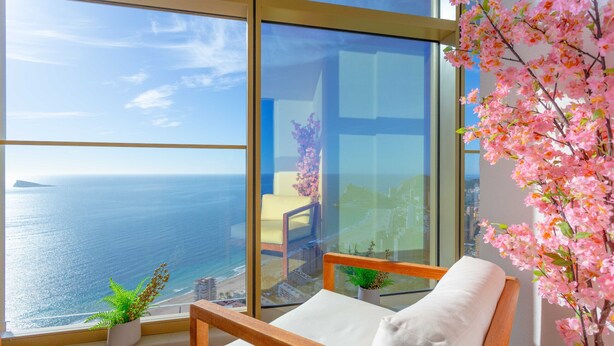 Un balcón con vista al mar, una silla y una planta en maceta.