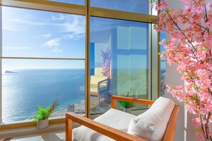 Un balcone con vista sul mare, una sedia e una pianta in vaso.