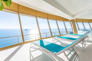 A sunlit deck with lounge chairs facing a large window overlooking the sea. - Intempo by Holuxe - 205 - 20th floor (Benidorm)
