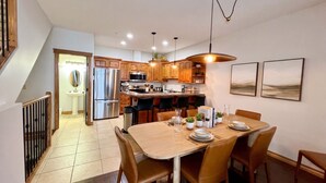 Una cocina moderna con armarios de madera, electrodomésticos de acero inoxidable y un comedor con mesa y sillas de madera.