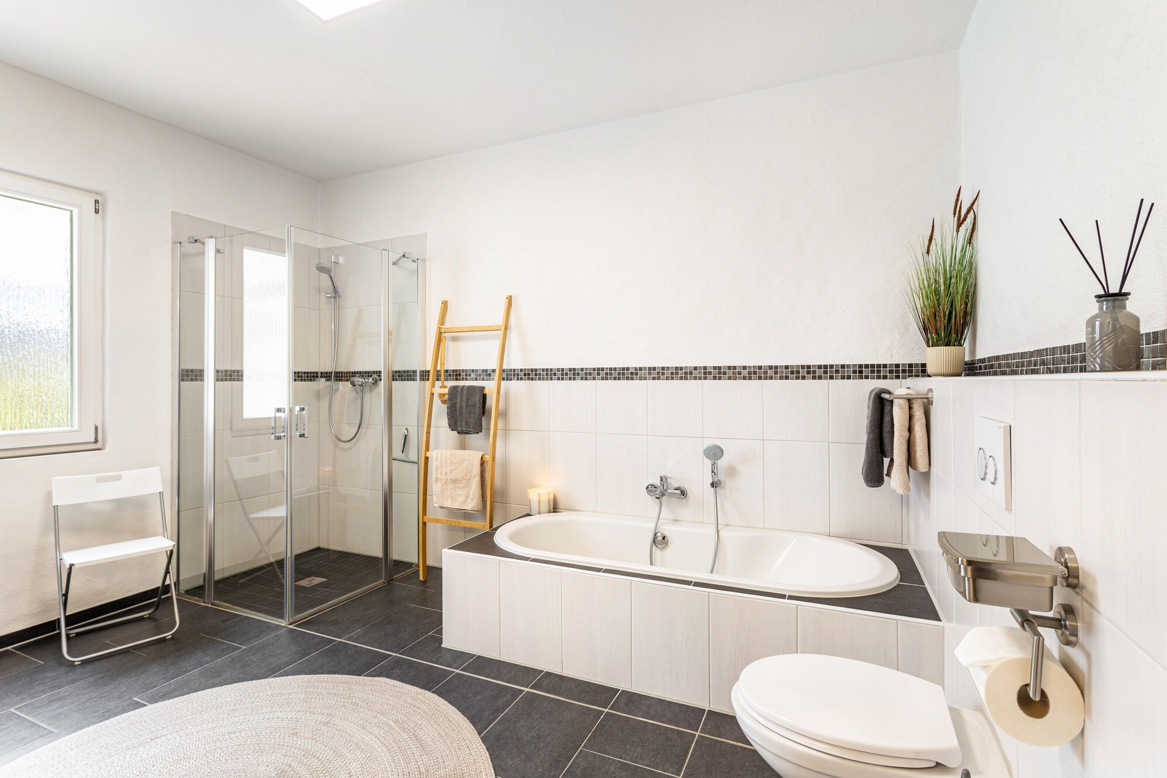 Un baño moderno con ducha de vidrio, bañera independiente, inodoro y lavamanos.