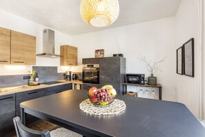 Een moderne keuken met een centraal eiland, houten kasten, een magnetron en een fruitschaal.