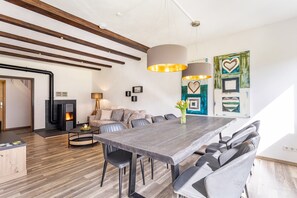Een moderne eetruimte met een lange tafel, stoelen en hanglampen.