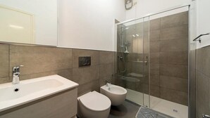 Ett modernt badrum med en stor tvättställ, två toaletter, en bidé och en dusch med glasväggar.