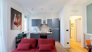 A compact bedroom with a bed, a small desk, and a kitchenette. - Bright Modern and Cozy Two-room Apartment - Convenient Parking & Fast Wi-Fi (Vercelli)
