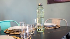 A table set with plates, glasses, and a water bottle. - Bright Modern and Cozy Two-room Apartment - Convenient Parking & Fast Wi-Fi (Vercelli)