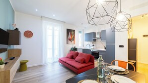 A modern living space with a dining area, kitchen, and a red sofa. - Bright Modern and Cozy Two-room Apartment - Convenient Parking & Fast Wi-Fi (Vercelli)