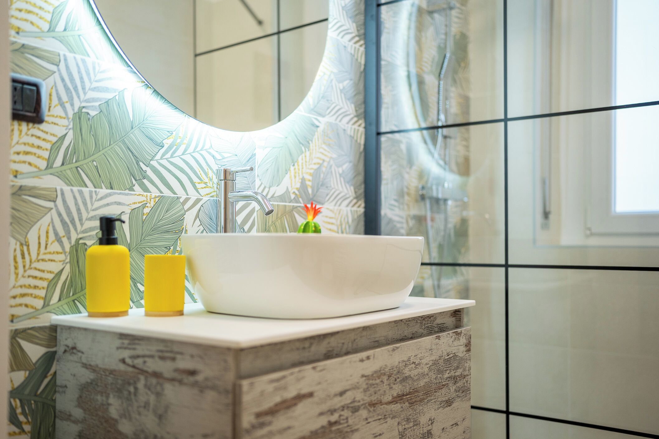 Ein Badezimmer mit einem weißen Waschbecken, einer gelben Flasche und einer weißen Schale auf einer Holzauslage.