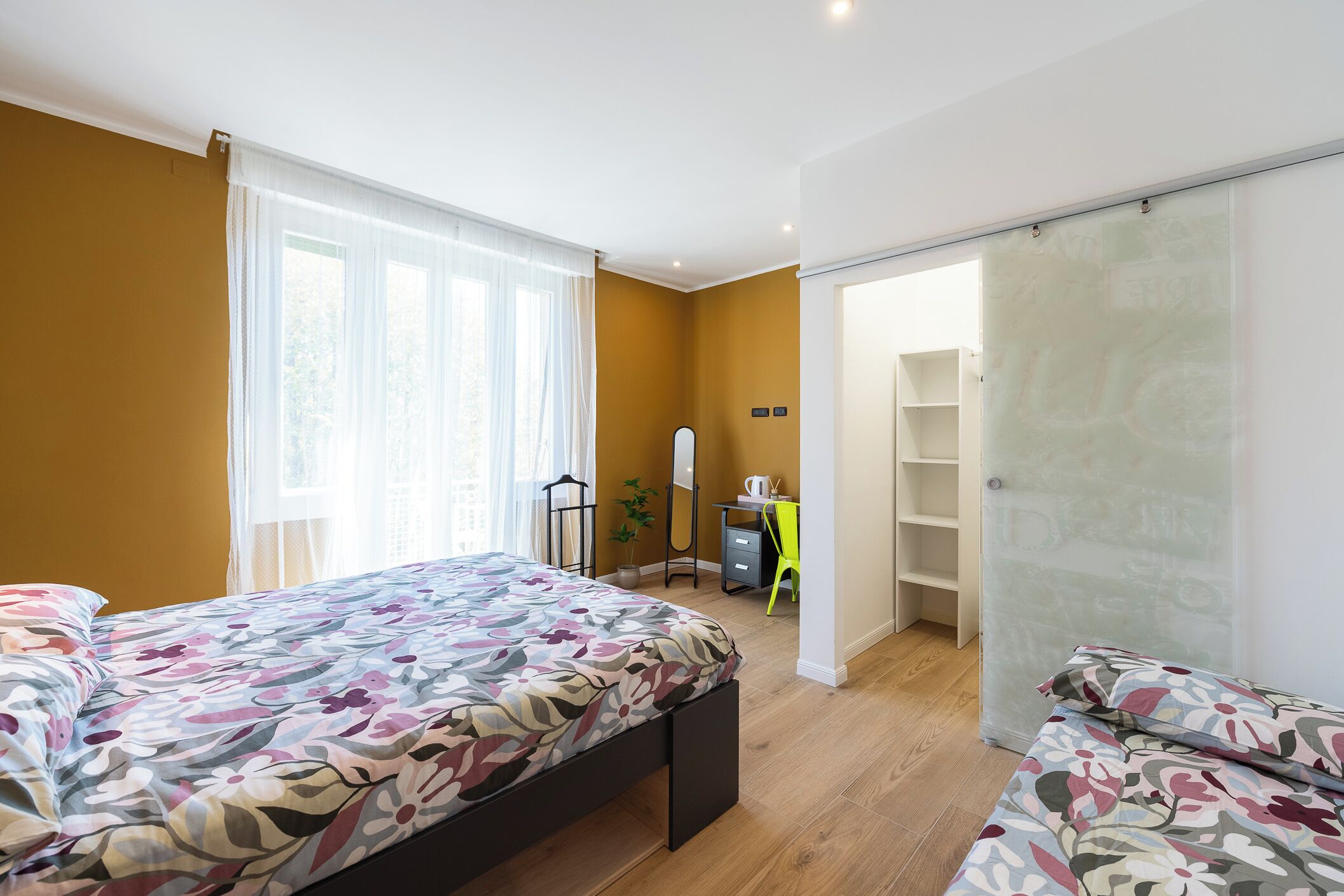 A bedroom with two beds, a desk, and a wardrobe.