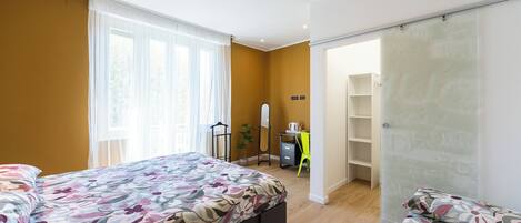 A bedroom with two beds, a desk, and a wardrobe.