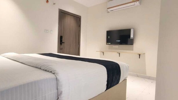 A bedroom with a bed, a television mounted on the wall, and a door. - FRACSPACE PRIVATE LIMITED (Hyderabad)