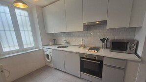 Eine moderne Küche mit Waschmaschine, Backofen, Mikrowelle und einem Fenster für natürliches Licht.