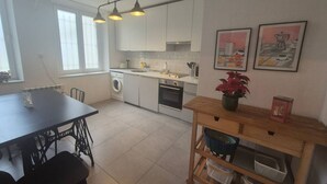 Una cocina moderna con armarios blancos, una mesa de comedor y un aparador de madera.