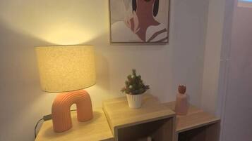A bedside table with a lamp, a small potted plant, and a decorative item.