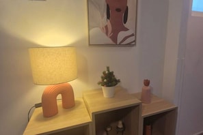 Una mesita de noche con una lámpara, una pequeña planta en maceta y un objeto decorativo.