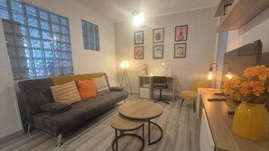 Una sala de estar moderna con un sofá, dos mesas redondas, un escritorio y una silla.
