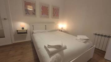 A hotel room with a bed, bedside tables, wall art, and a radiator.
