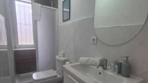 Un baño con inodoro, lavamanos y cabina de ducha.