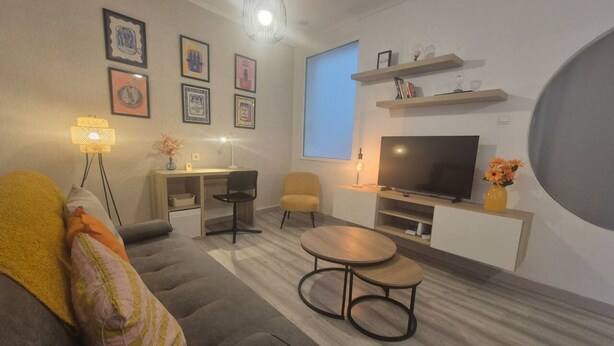 Una sala moderna con un sofá, una mesa de centro, un televisor y un escritorio con una silla.