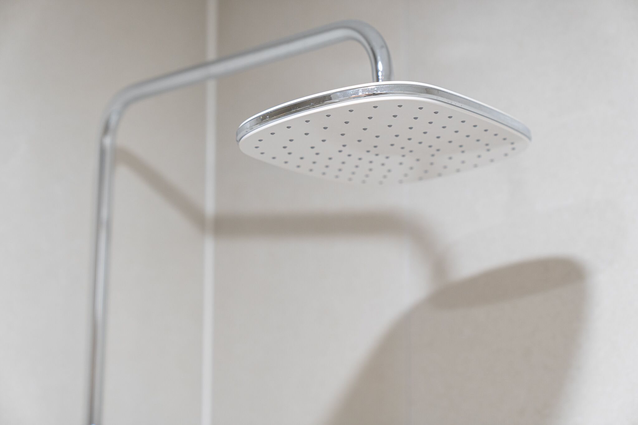 Un pommeau de douche au design incurvé et à la surface perforée.